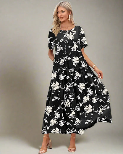 Woman in a black floral dress standing on a wooden deck with palm trees and ocean in the background